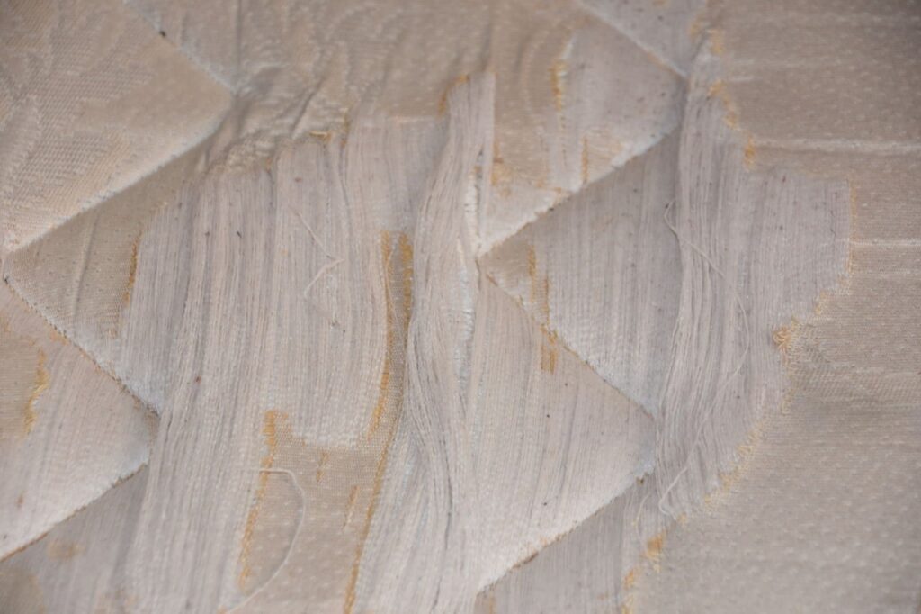 alt="Gross dorm mattress with stains and vinyl protector"