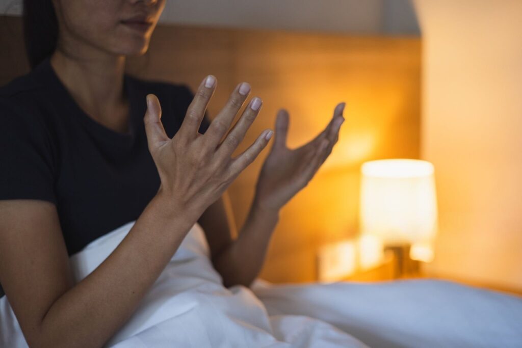 Woman frustrated in bed touching scratchy sheets at night