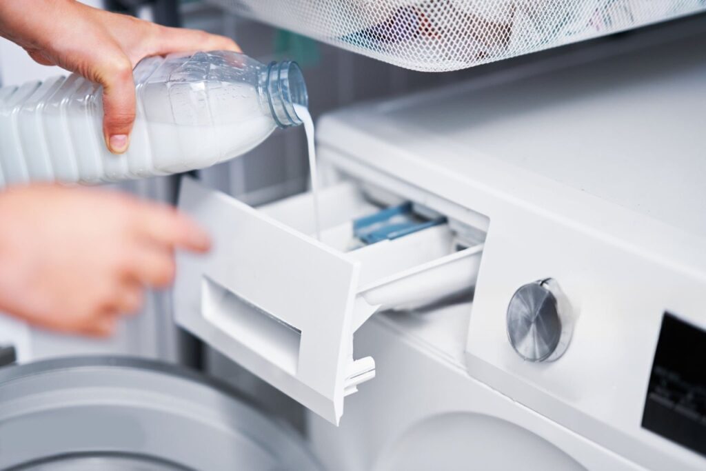 Close-up of clear white vinegar being poured into washing machine dispenser