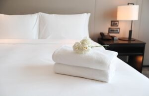 “A cozy bed with crisp white sheets, fluffy pillows, and soft lighting.”